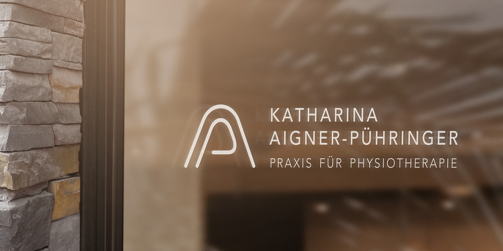 Logo mit Schriftzug der Praxis für Physiotherapie von Katharina Aigner-Puehringer abgebildet auf der Scheibe eines Schaufensters der Praxis.