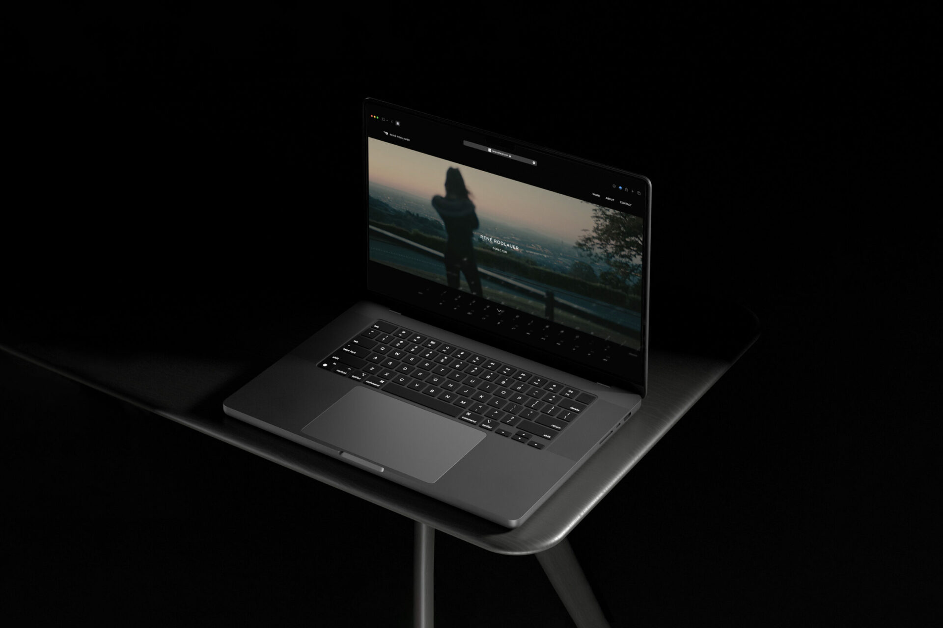 Aufgeklapptes Macbook mit Website und Logo im linken oberen Eck von René Rodlauer auf dunklem Hintergrund.